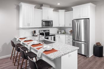 A kitchen with a marble counter top and stainless steel refrigerator
